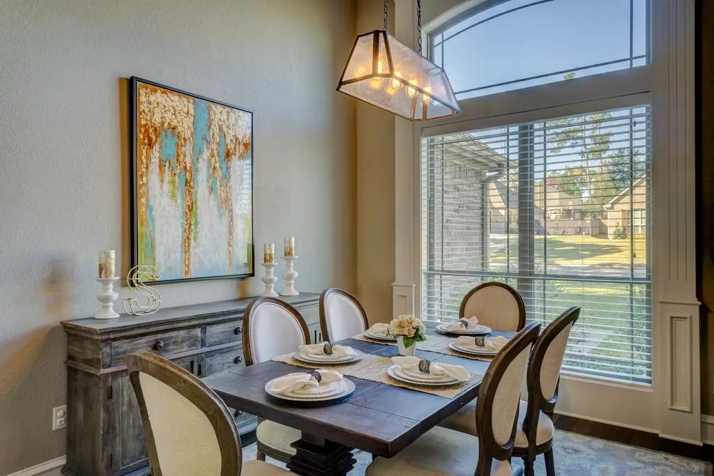 Dining room with blinds on tall windows and a statement pendant