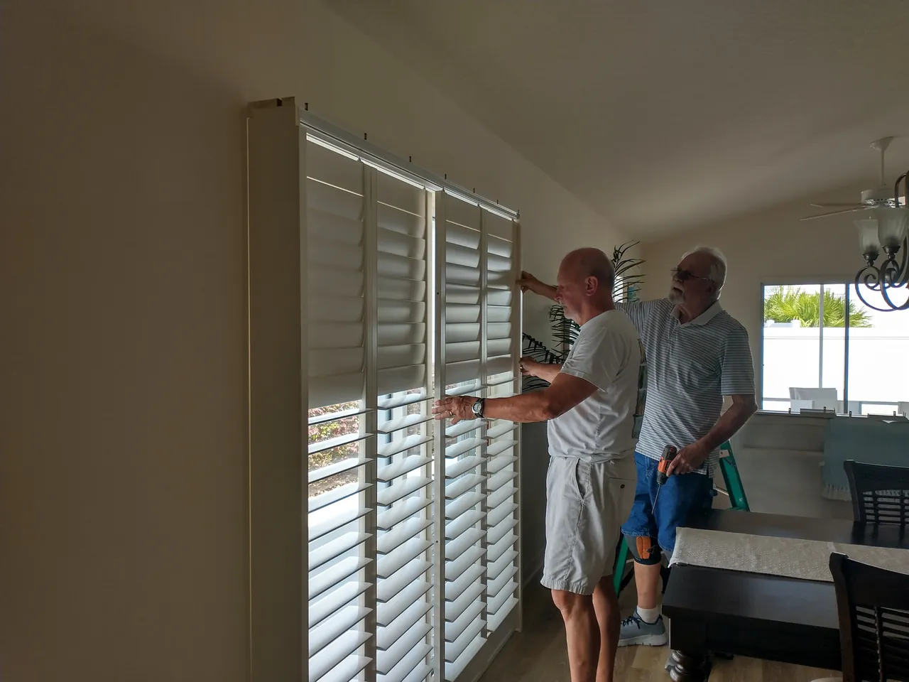 Installers fitting plantation shutters on a patio door