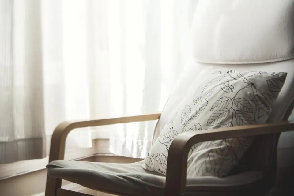 Sheer curtains behind a reading chair and cushion